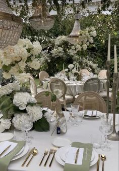 the table is set with white flowers and place settings for an elegant dinner party or celebration