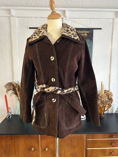 Vintage 1970's chocolate brown suede leather jacket with tie faux fur belt and collar. Button closure and pockets.  In fab vintage condition, with no rips or stains to the fabric. Would fit a modern U.K. 10. Era: 1970's  Brand: Unbranded Bust: 36 inches  Waist: 30 inches  Length: 28 inches  Sleeve Length: 23 inches  All sales are final, no returns or refunds. Retro Brown Outerwear With Faux Fur Lining, Vintage Brown Outerwear With Faux Fur Trim, Retro Brown Outerwear With Faux Fur Trim, Leather Jacket With Tie, Fur Belt, Brown Suede Leather Jacket, Brown Suede Jacket, Faux Fur Collar, Suede Jacket