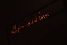 a neon sign that says all you need is love in red writing on a black background