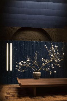 a vase with white flowers sitting on top of a wooden table in front of a blue wall