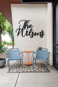 two blue chairs sitting on top of a cement floor next to a white brick wall