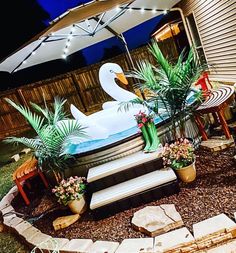 a large white swan sitting on top of a bench next to a garden area with potted plants