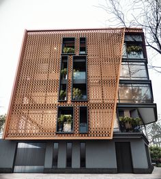 the building has many windows and plants growing on it's sides, along with several balconies