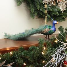 a peacock figurine sitting on top of a wooden shelf next to a christmas tree