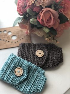 two crocheted purses sitting on top of a table next to a bouquet of flowers