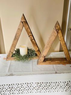 two wooden triangle shaped candlesticks sitting next to each other on a white table