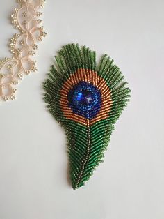 beaded brooch with peacock feather on white background