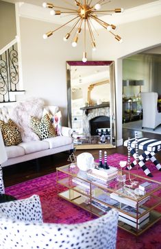 a living room filled with furniture and a chandelier hanging from the ceiling above it