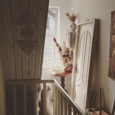 a white dog sitting on top of a wooden stair case next to a door and window