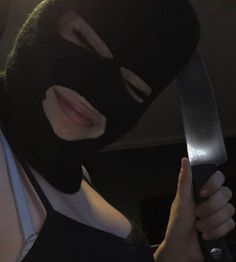 a woman wearing a black mask holding a knife