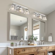 a bathroom with two sinks and three lights on the mirror above it is also a bathtub