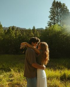 a man and woman embracing each other in front of the sun on a sunny day