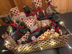 a large basket filled with lots of wrapped presents on top of a black table next to a wooden wall