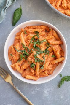 two bowls filled with pasta and sauce on top of a table