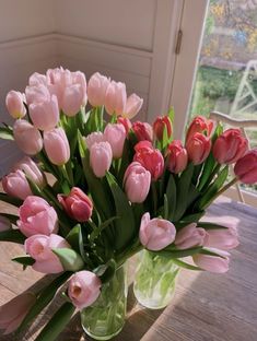 a vase filled with pink tulips on top of a wooden table