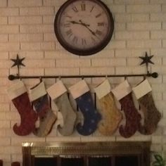 stockings hung on the mantle in front of a clock and fireplace mantel with christmas stockings hanging from it