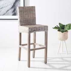 a wicker bar stool next to a potted plant in a white living room