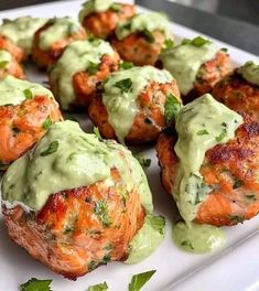 some meatballs covered in green sauce on a white plate