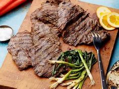 steak, asparagus and orange slices on a cutting board with knife and fork