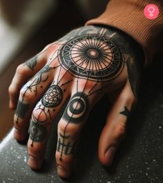 a person's hand with tattoos on it and an ornamental wheel tattooed on the palm