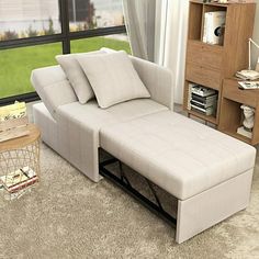 a living room with a couch, coffee table and bookcase in front of a large window