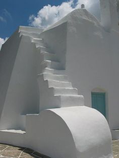 a white building with steps leading up to the door and sky in the back ground