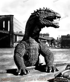 an old photo of a godzilla statue in front of a car