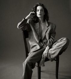 a black and white photo of a woman sitting in a chair with her hand on her head