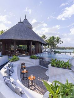 an outdoor seating area next to a swimming pool and gazebo with palm trees in the background