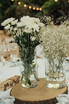 two vases filled with white flowers sitting on top of a wooden table next to each other