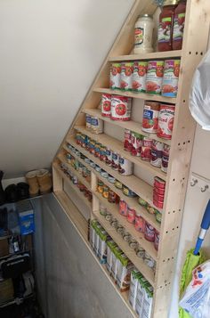 an organized pantry under the stairs in a loft space with shelves full of canned food