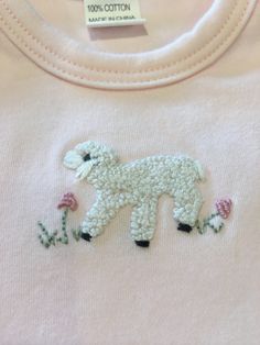 a close up of a shirt with a sheep on the front and flowers in the back