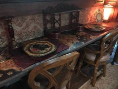 an old fashioned dining room table and chairs with plates on it, next to a lamp