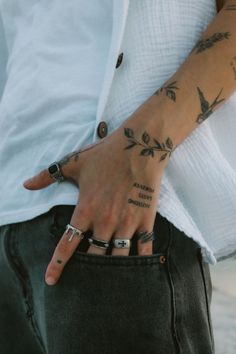 a person with tattoos on their arm and hand holding onto the pocket of his pants