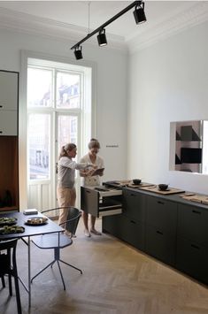 two people standing in a kitchen preparing food