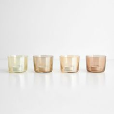 three different colored glass cups sitting next to each other on a white counter top,