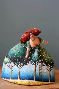 a ceramic figurine is sitting on top of a wooden table with trees and a woman