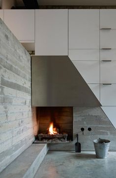 a fire place in a kitchen next to a wall with cabinets and drawers on it