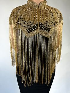 the back of a woman's dress with gold beading and fringes on it