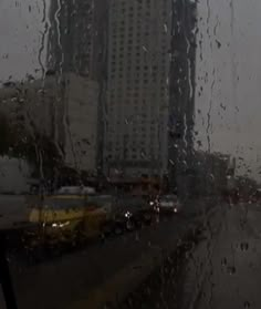 rain is pouring down on the windshield of a car in front of a tall building