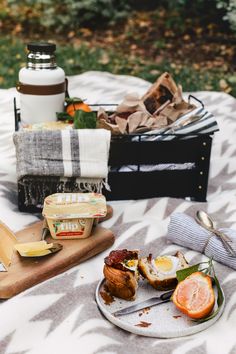 an outdoor picnic with food and drinks on the table, along with utensils