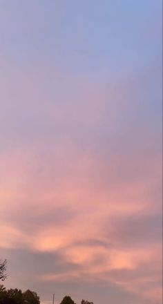 an airplane is flying in the sky at sunset or dawn with clouds and trees around it