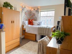 a bedroom with a bed, dresser and plant in the corner on top of it