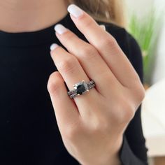 a woman's hand with a ring on it and a black diamond in the middle