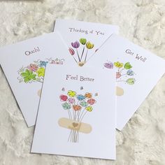 three greeting cards with flowers on them sitting on a white surface next to each other