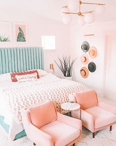 a bedroom with pink chairs and a bed in the corner, along with pictures on the wall