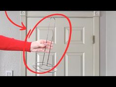 a person holding an object in front of a door with red arrows pointing to it