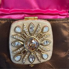 a gold and white brooch sitting on top of a brown bag with diamonds in it