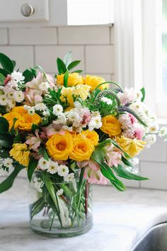 a glass vase filled with yellow and white flowers