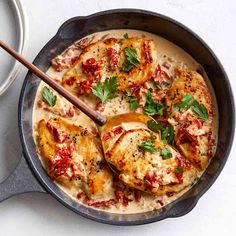 a pan filled with chicken covered in sauce and garnished with parsley